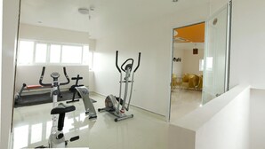 A gym with exercise equipment, a mirror, and a door leading to a dining area. - Van Mieu 2 Hotel (Hanoi)