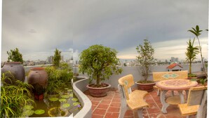 A rooftop terrace with potted plants, a small water feature, and outdoor seating. - Van Mieu 2 Hotel (Hanoi)