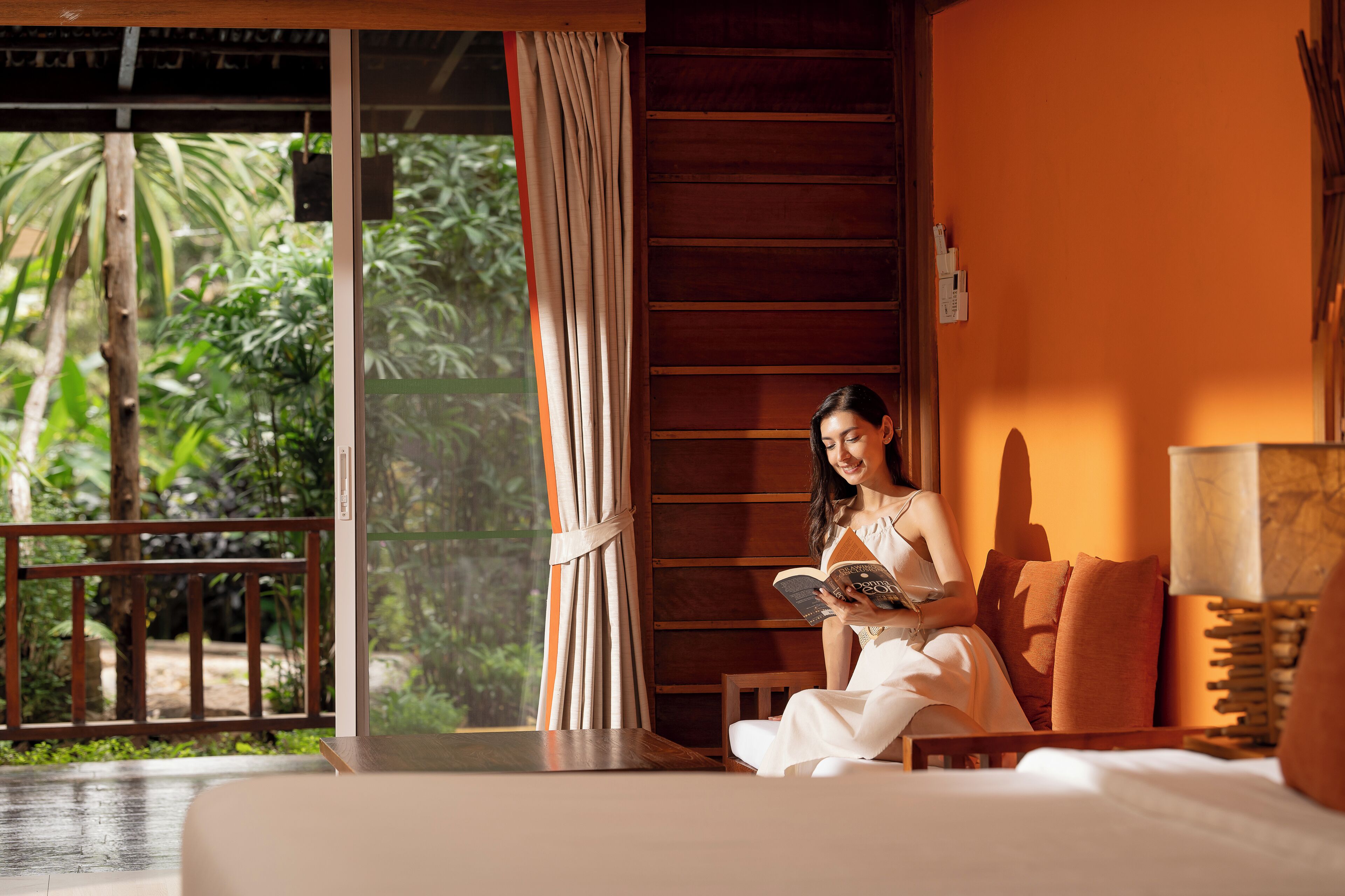 A room with a large window, a bed, and a reading area.