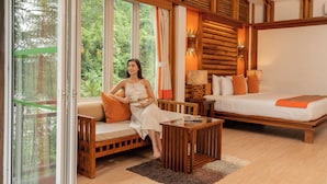 A cozy room with a wooden bed, a sofa, and a glass door leading to a balcony.