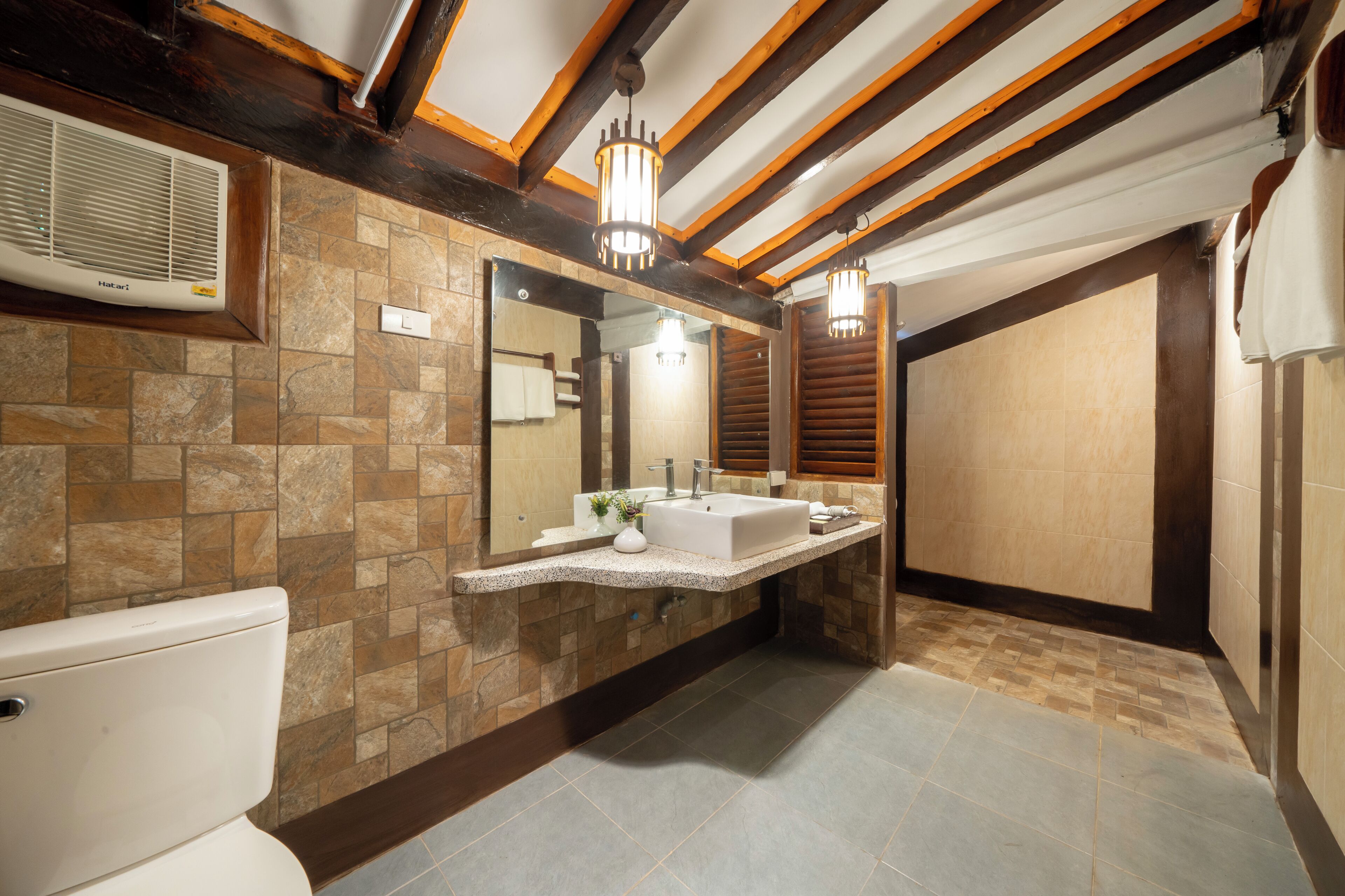 A modern bathroom with a stone tile backsplash, a white sink, and a large mirror.