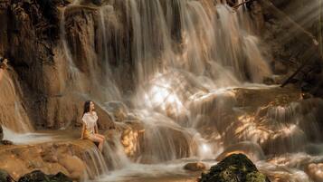 A waterfall with a person sitting on a rock.