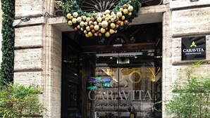 A hotel entrance with a large archway, a wreath, and the name 'CARAVITA' on the door. - Hotel Caravita (Rome)