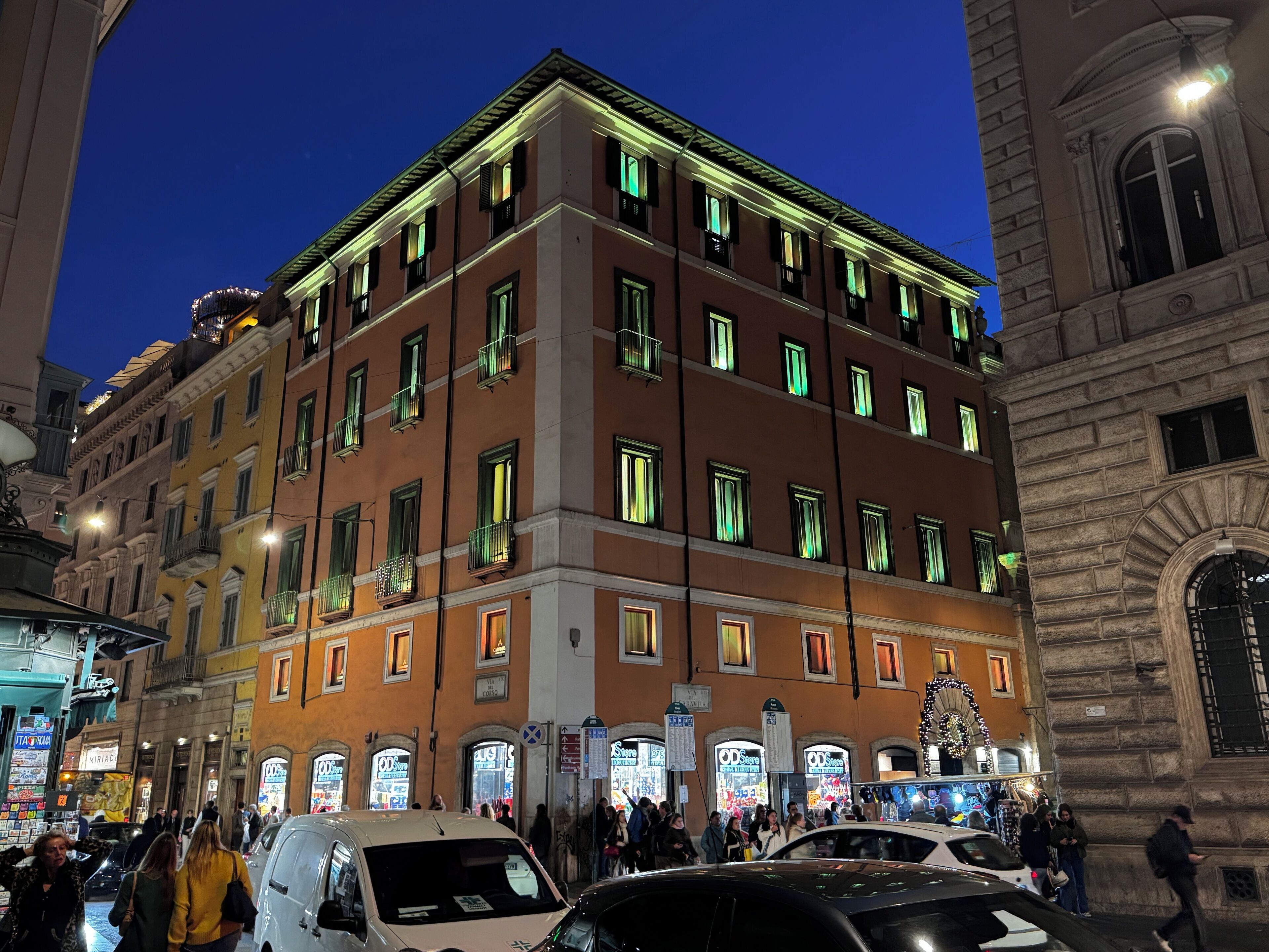 A multi-story building with a ground floor featuring storefronts, a central entrance, and a staircase leading to the upper floors.