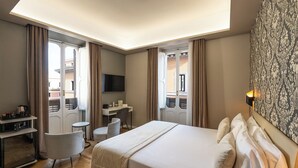 A hotel room with a bed, desk, chair, television, and a view of the outside. - Hotel Caravita (Rome)