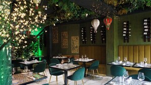 A restaurant with tables set for dining, green chairs, and a decorative ceiling. - Hotel Caravita (Rome)
