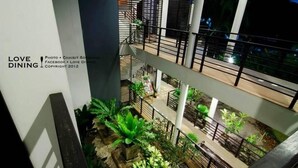 Een meerlaags atrium met binnenplanten en een trap.