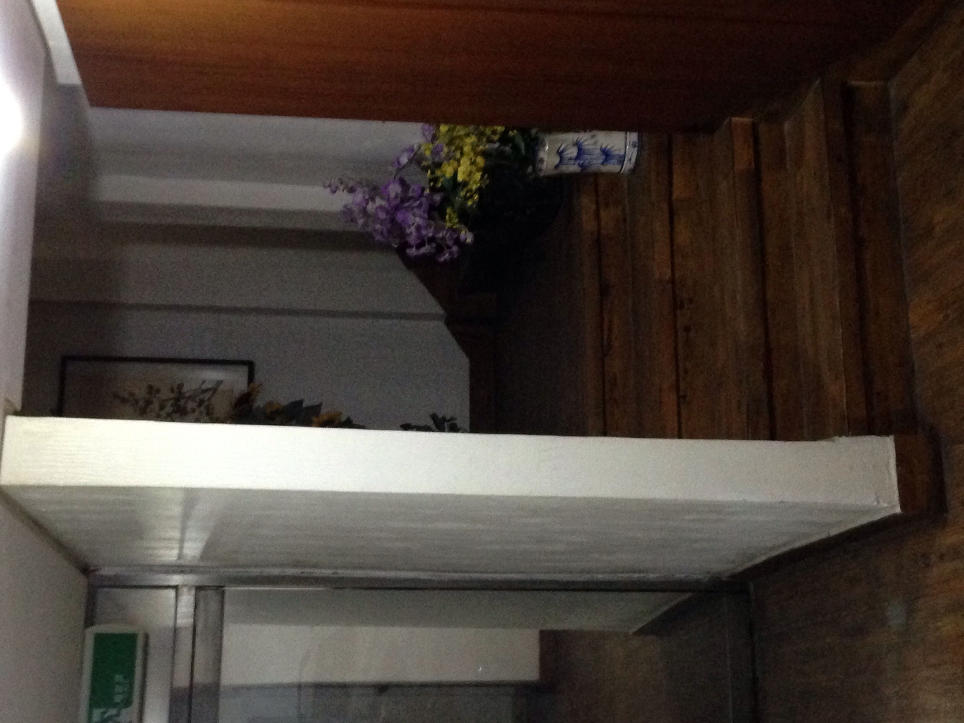 A narrow hallway with a wooden wall and a white shelf.