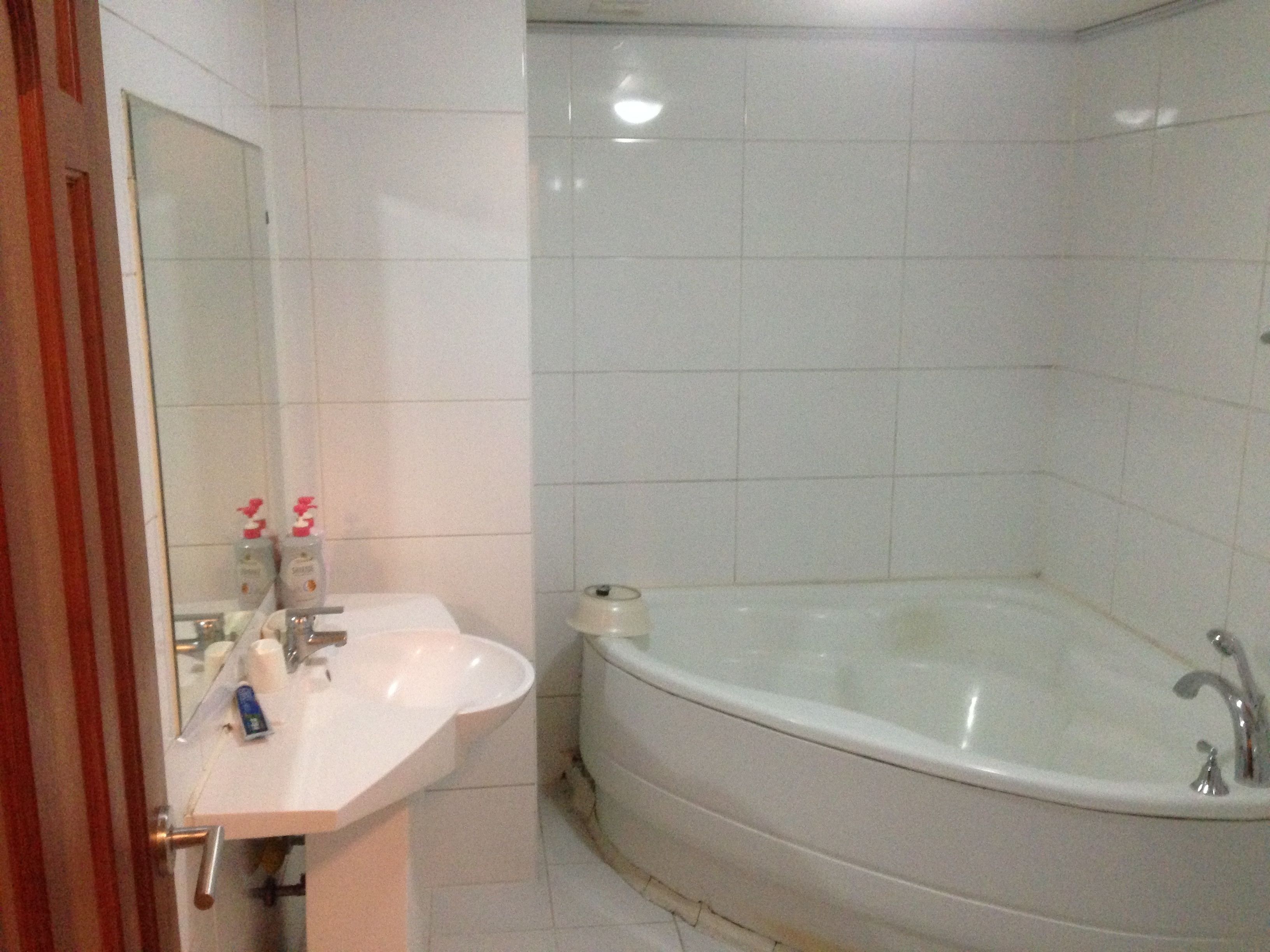 Un baño con lavamanos blanco, un espejo y una bañera.