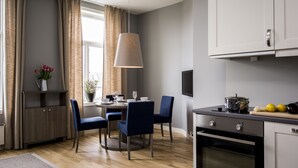 A modern kitchen with a dining table, chairs, a hanging light fixture, and an oven. - Frogner House - Oscars gate (Oslo)