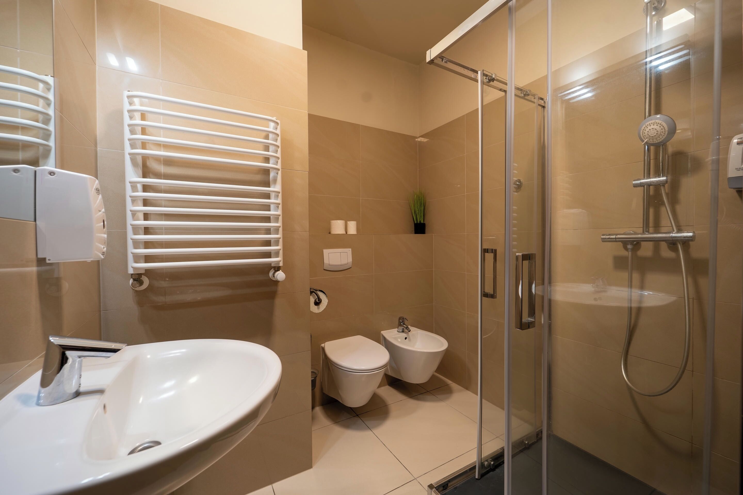 Une salle de bain moderne avec une douche à parois de verre, un lavabo blanc, des toilettes et un bidet.