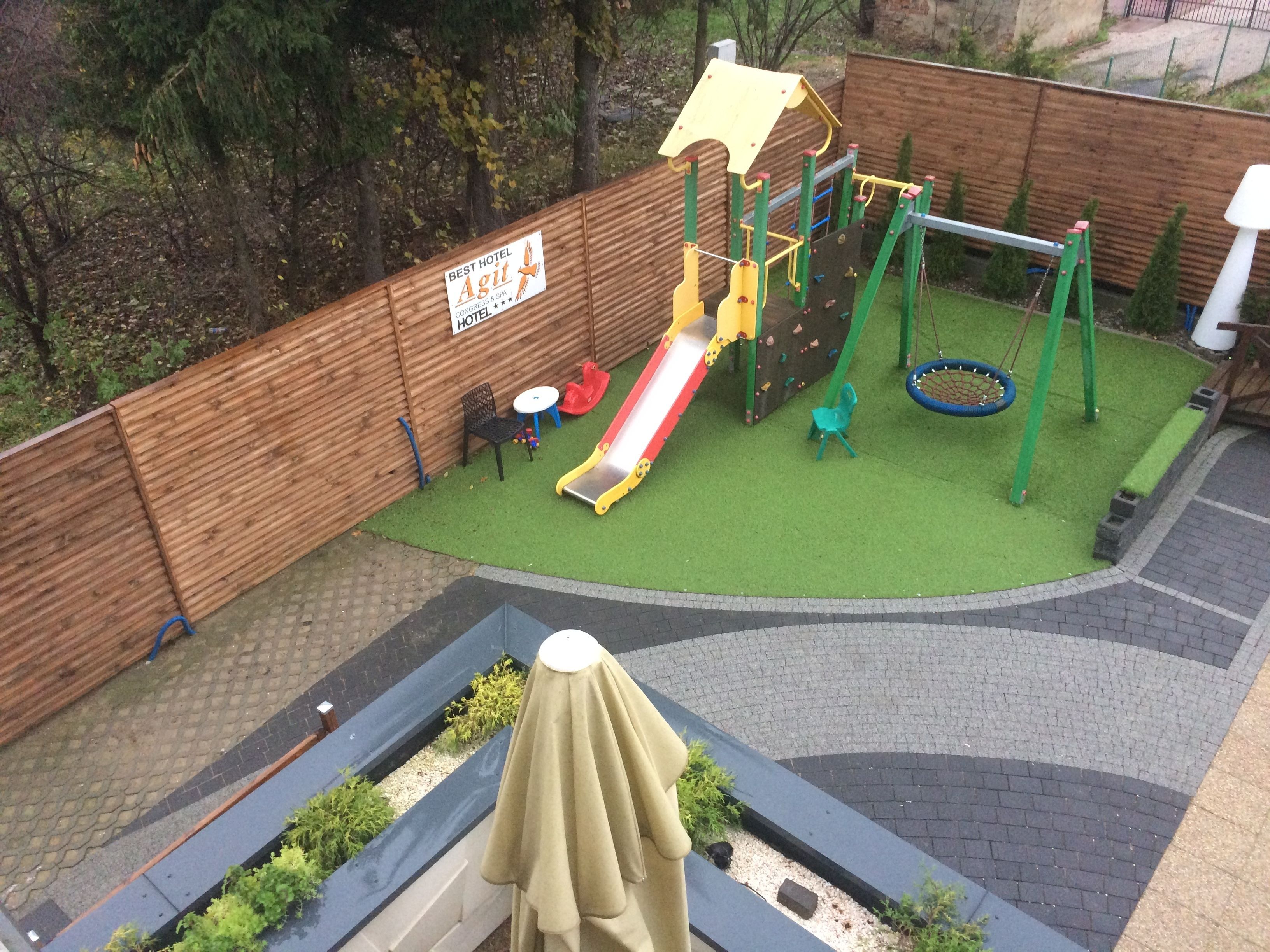 Un espace de jeux pour enfants avec un toboggan, des balançoires et des structures d’escalade.