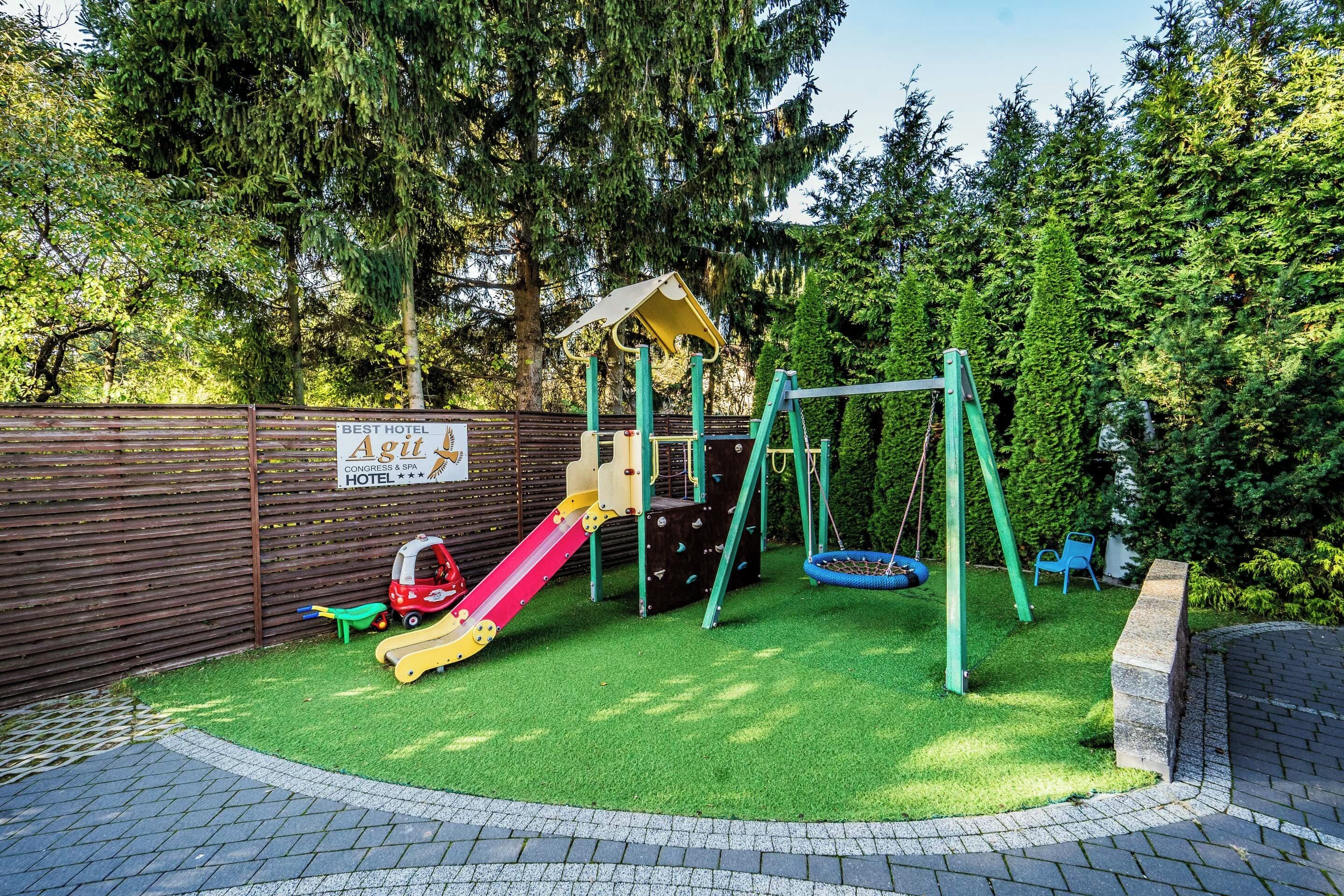 Ein Spielplatz mit Rutsche, Schaukeln und einer Kletterkonstruktion.
