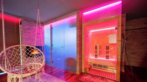 Une pièce avec un fauteuil suspendu, un sauna et une porte en bois.