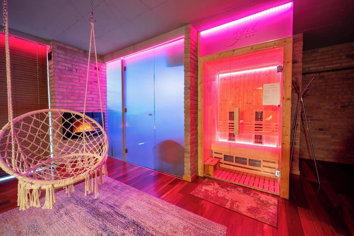 A room with a hanging chair, a sauna, and a wooden door.