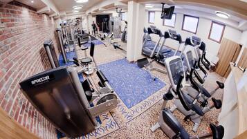 A gym with various exercise equipment, a blue patterned carpet, and brick walls.
