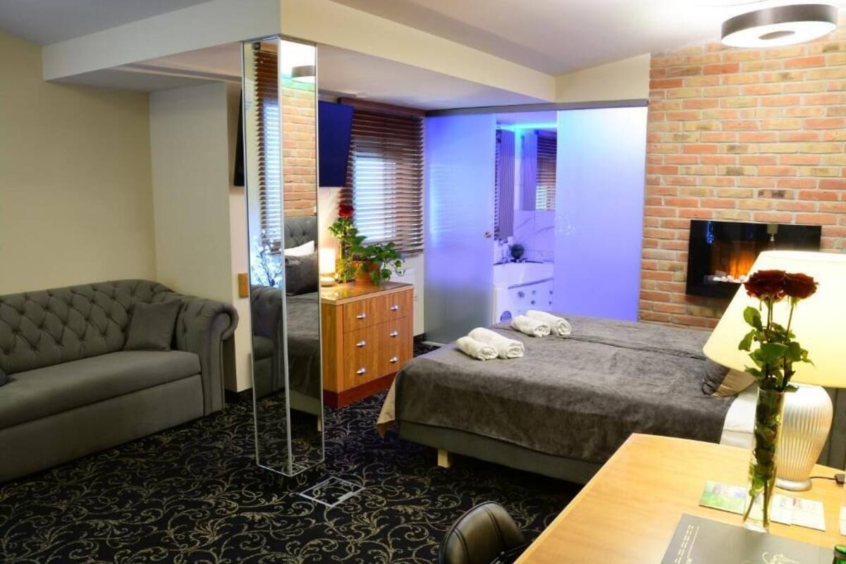 A hotel room with a sofa, a bed, a wooden dresser, a desk, and a TV.