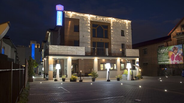 Un hôtel doté d’une façade moderne, d’une enseigne au néon bien visible et d’une entrée bien éclairée.