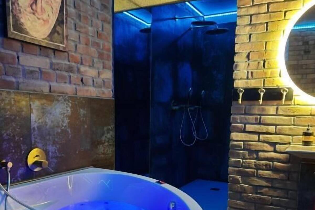 A spa area with a hot tub, a brick wall, and a circular mirror.