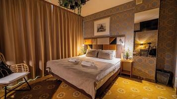 Una habitación de hotel ordenada con una cama grande, una silla, un escritorio con lámpara y un cubo de basura.
