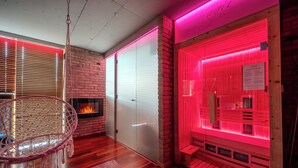 Une pièce avec une cheminée, un sauna et un fauteuil suspendu.