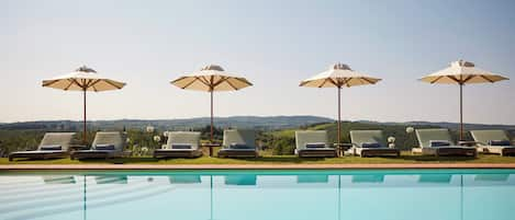 Una piscina al aire libre, sombrillas, tumbonas