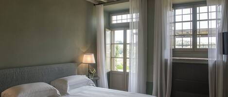 A bedroom with a bed, a nightstand, a lamp, and a window with curtains.