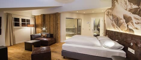 A modern bedroom with a large bed, a sofa, a desk, and a wooden accent wall.