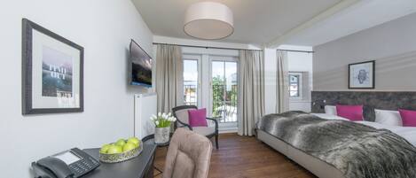 Une chambre d’hôtel avec un lit, un bureau doté d’un téléphone et d’un bol de pommes, une chaise et une grande fenêtre avec des rideaux.