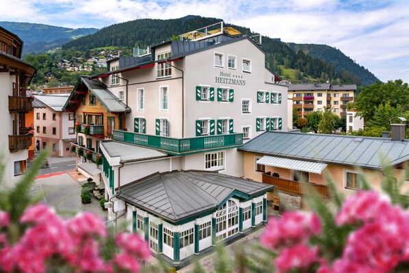 A hotel with multiple floors, balconies, and a view of the surrounding town and mountains. - HEITZMANN - Hotel & Rooftop (Zell am See)