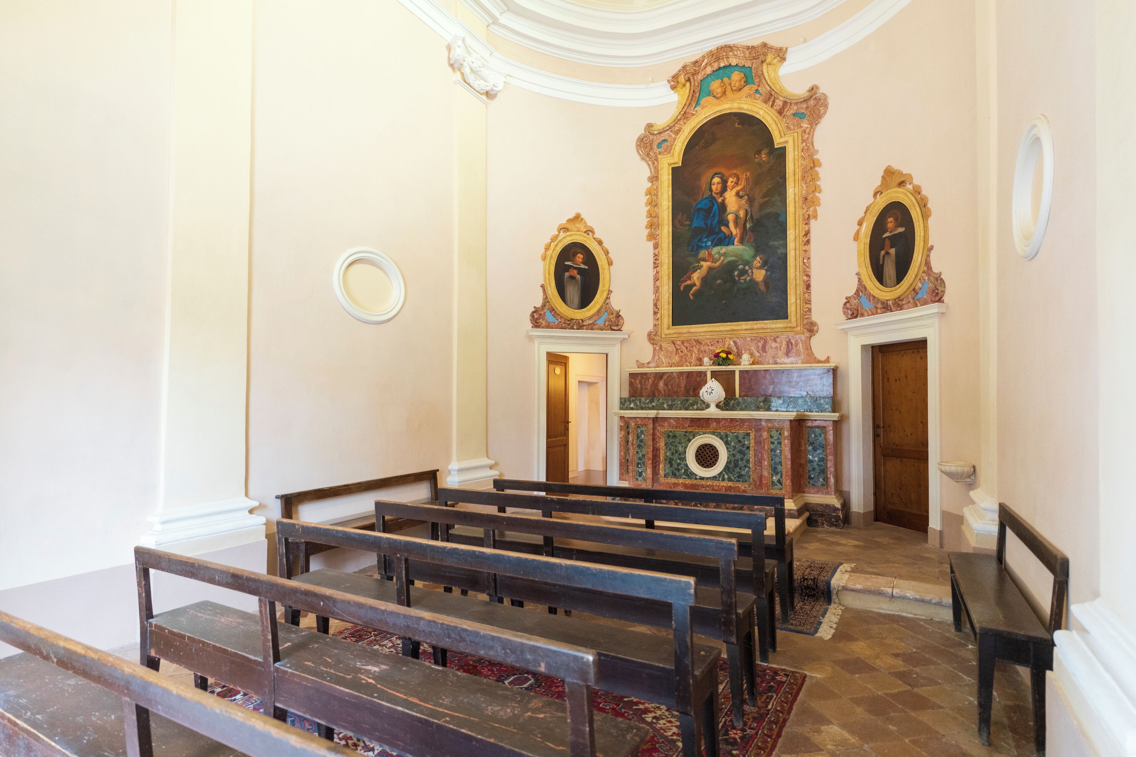 A church interior with pews, an altar, and religious paintings.