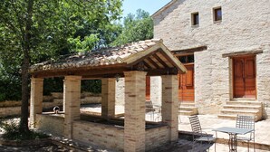 A stone building with a covered patio, outdoor seating, and a small pool. - Villa Rinalducci (Fano)