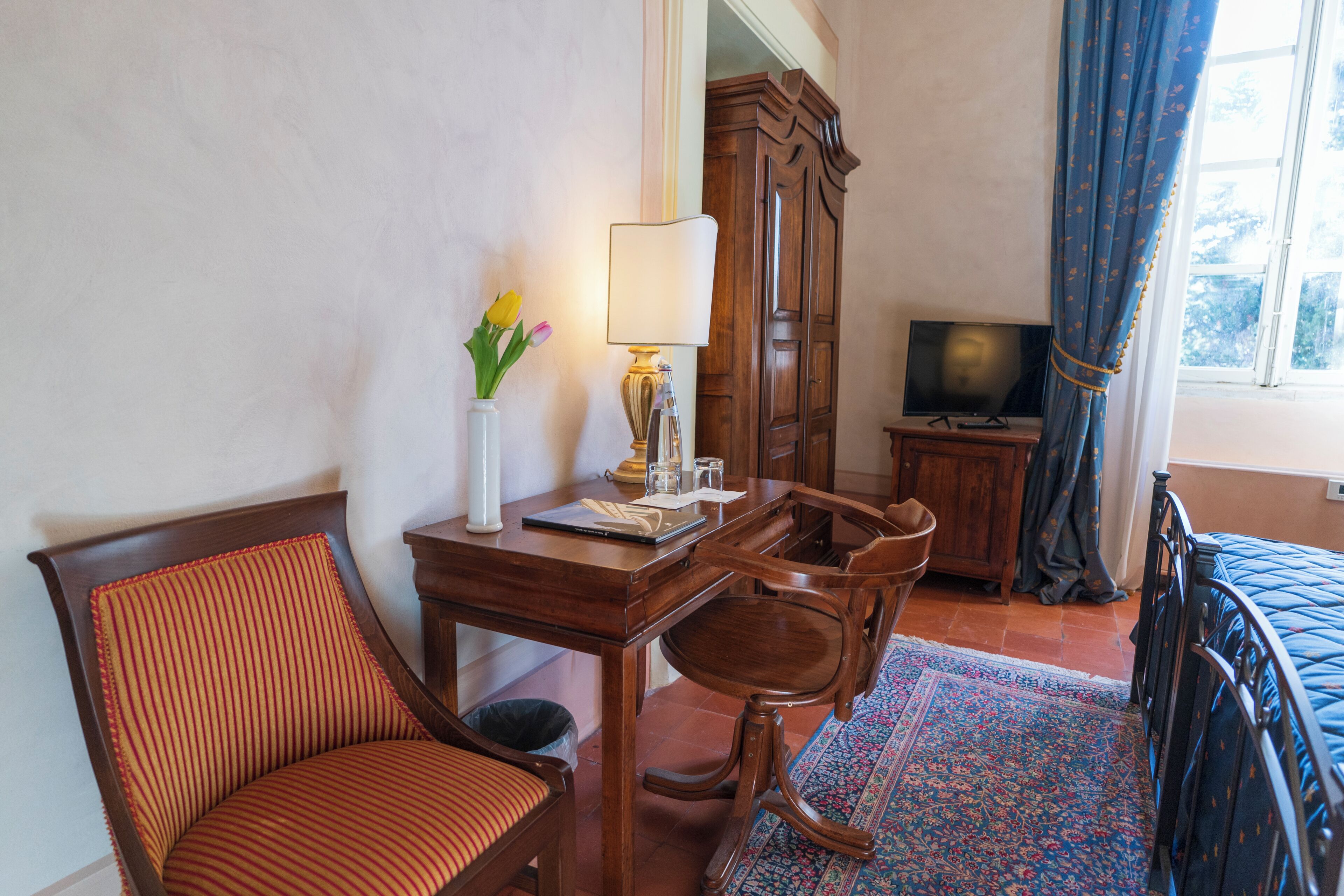 Una habitación de hotel con un escritorio de madera, una silla, un televisor y una cama.