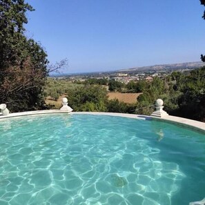 En säsongsöppen utomhuspool, parasoller och solstolar