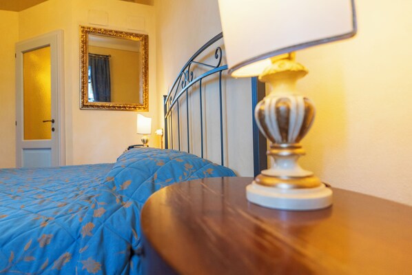 Una habitación de hotel con cama, lámpara de noche, espejo y puerta.