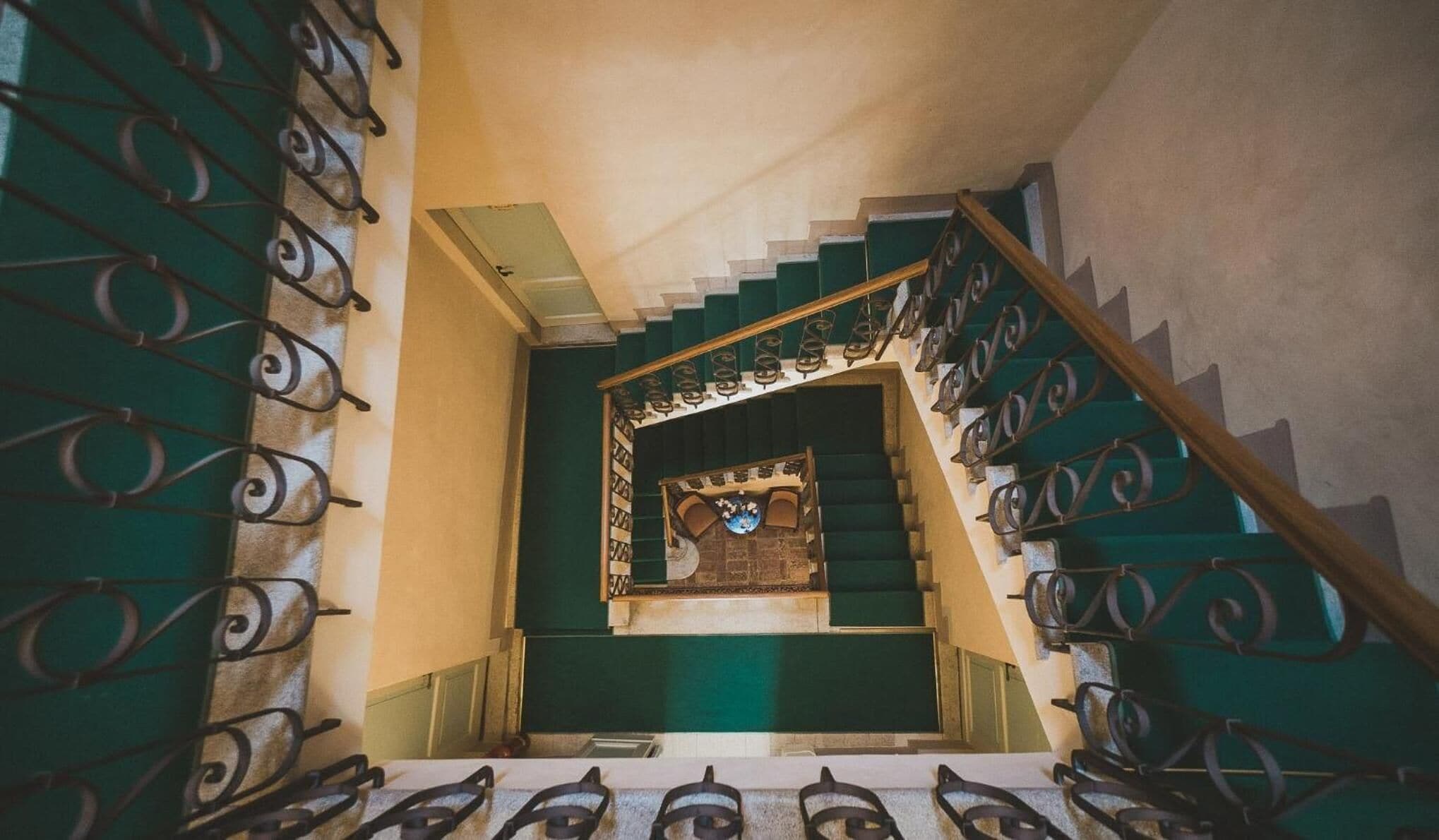 Eine Treppe mit grünen Stufen und aufwendig gestalteten Metallgeländern.
