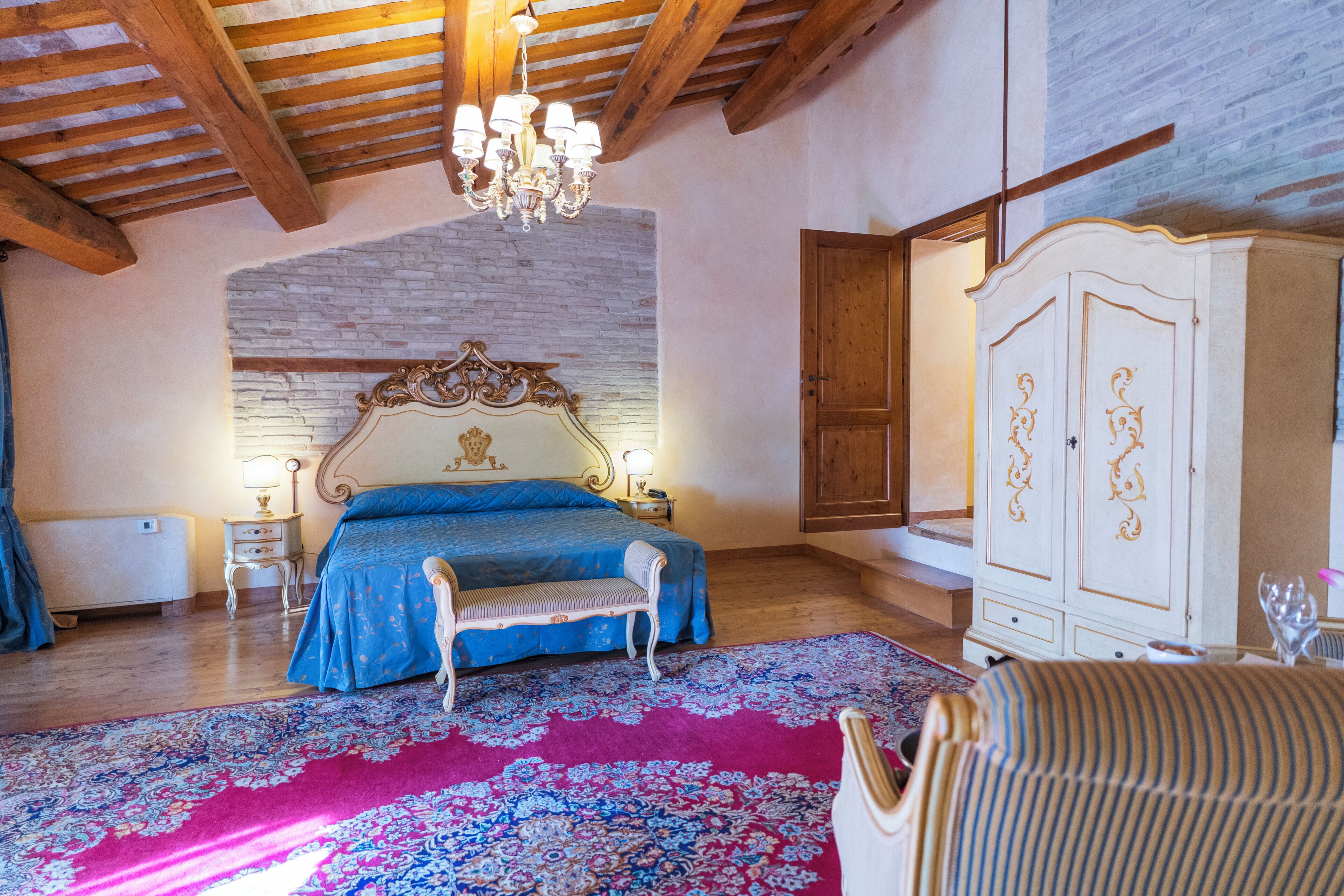 Ein Schlafzimmer mit einem Bett, einer Bank, einem Kleiderschrank und einer Chandelüster.