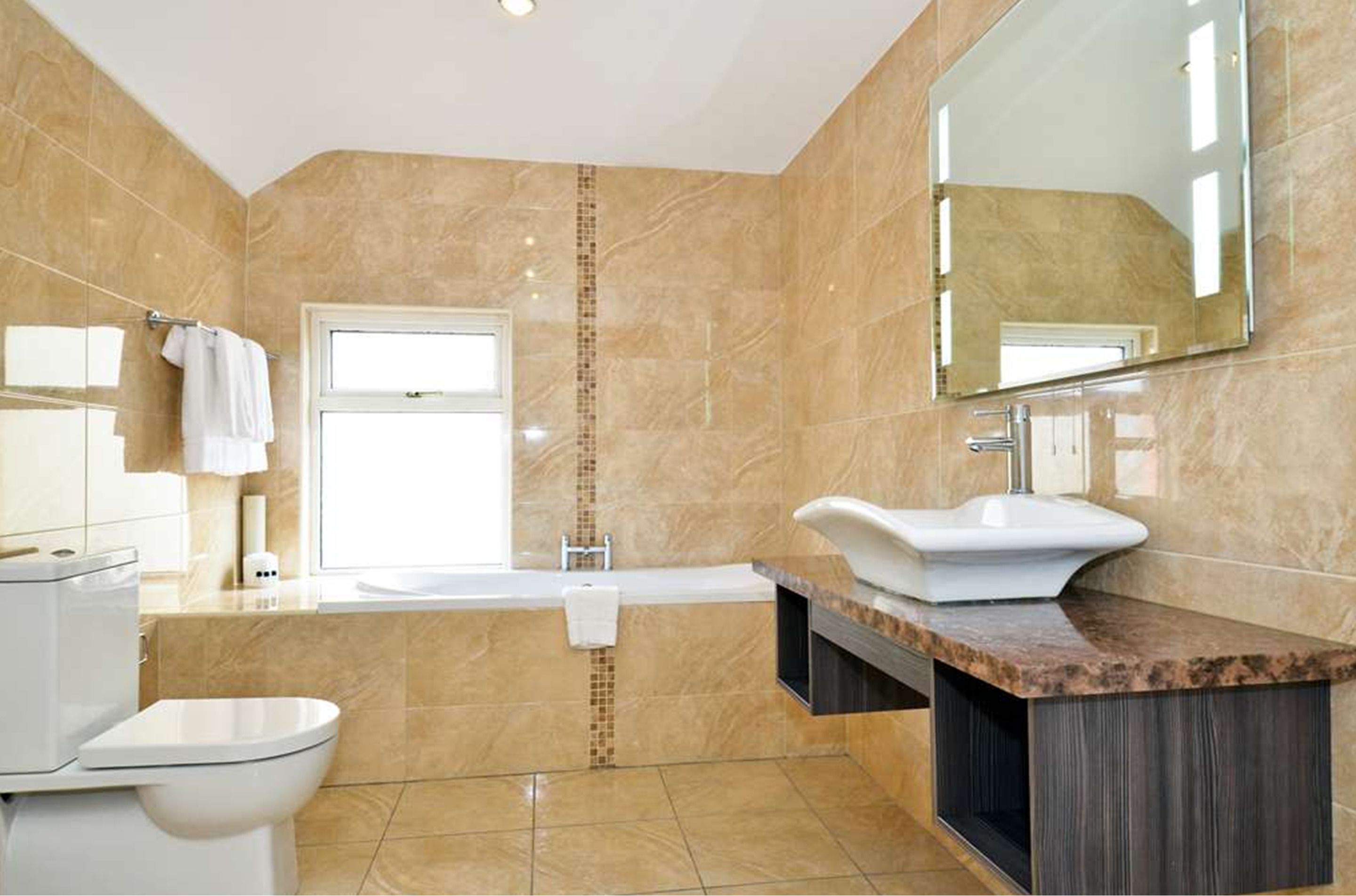 Een moderne badkamer met een wit toilet, een wastafel en een bad.