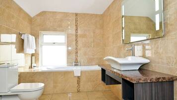 Een moderne badkamer met een wit toilet, een wastafel en een bad.