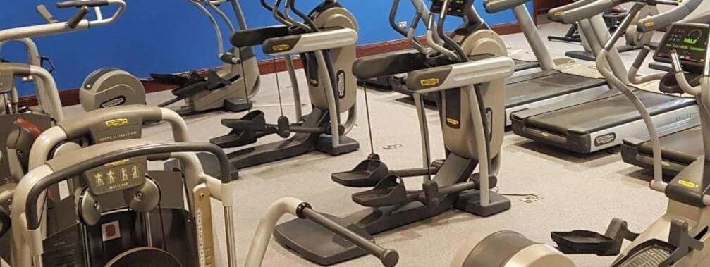 A gym with various exercise equipment including treadmills and elliptical machines.