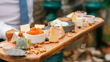 A wooden board with various cheeses, nuts, and fruits.