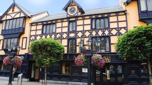 Un edificio de estilo Tudor tradicional con fachada negra y amarilla, ventanas grandes y un reloj.