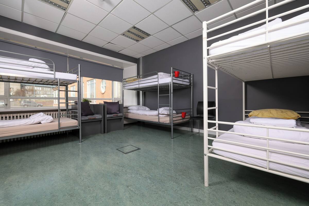 Un dormitorio con literas, una ventana y un radiador.