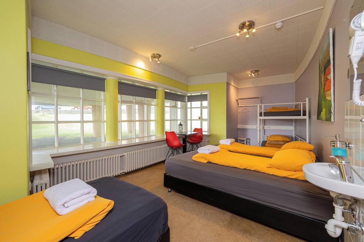 Una habitación de hotel con cama, escritorio, silla, ventana y baño.