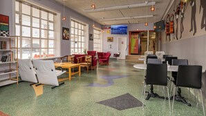 A spacious room with large windows, a television, and a wall decorated with musical instruments. - Hostel B47 (Reykjavik)