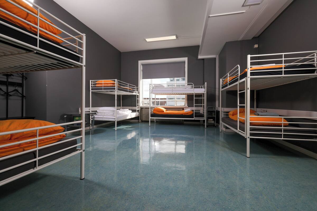 Habitación tipo dormitorio con literas, una ventana y un radiador.