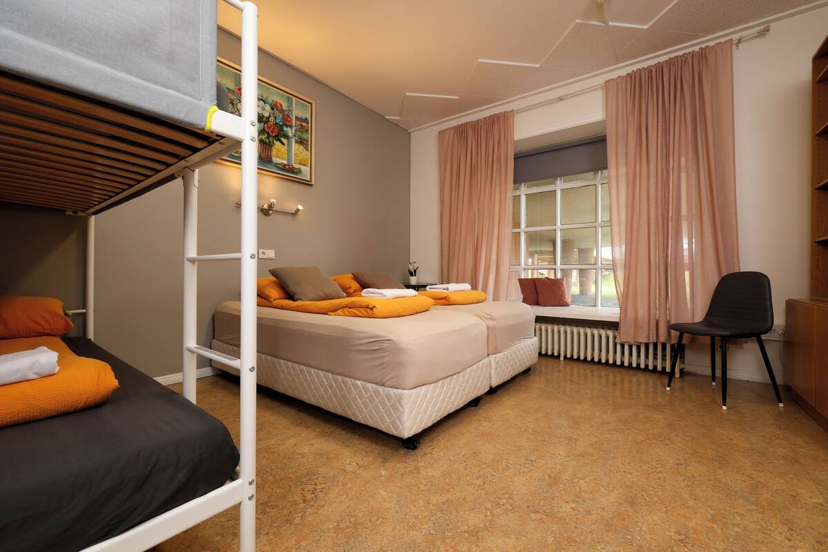 Habitación tipo dormitorio con literas, un escritorio y una ventana con cortinas.