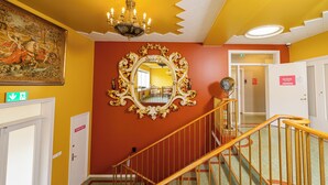 A staircase with a golden handrail, a large ornate mirror, and a painting on the wall. - Hostel B47 (Reykjavik)