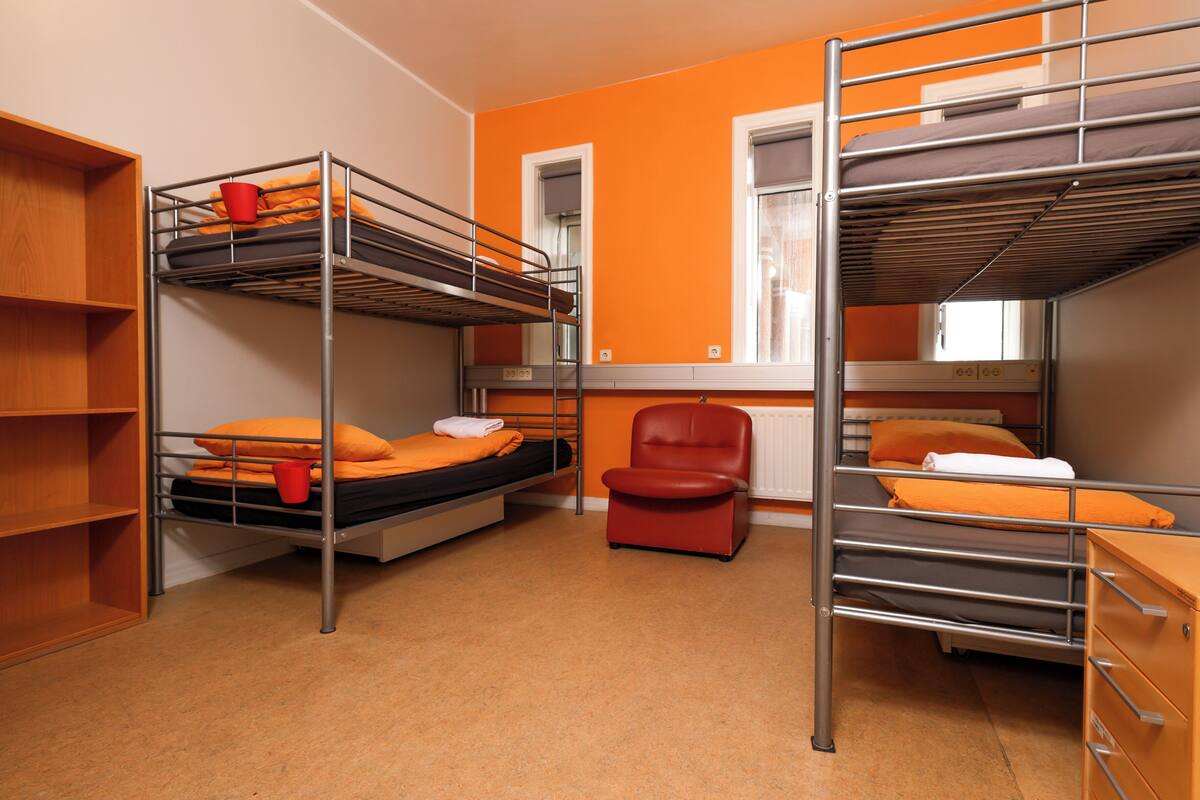 Un dormitorio con literas, una silla roja y un armario de madera.
