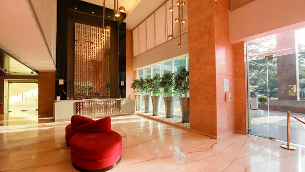 A spacious lobby with a red chair, a reception desk, and a decorative wall. - E Hotel (Chennai)